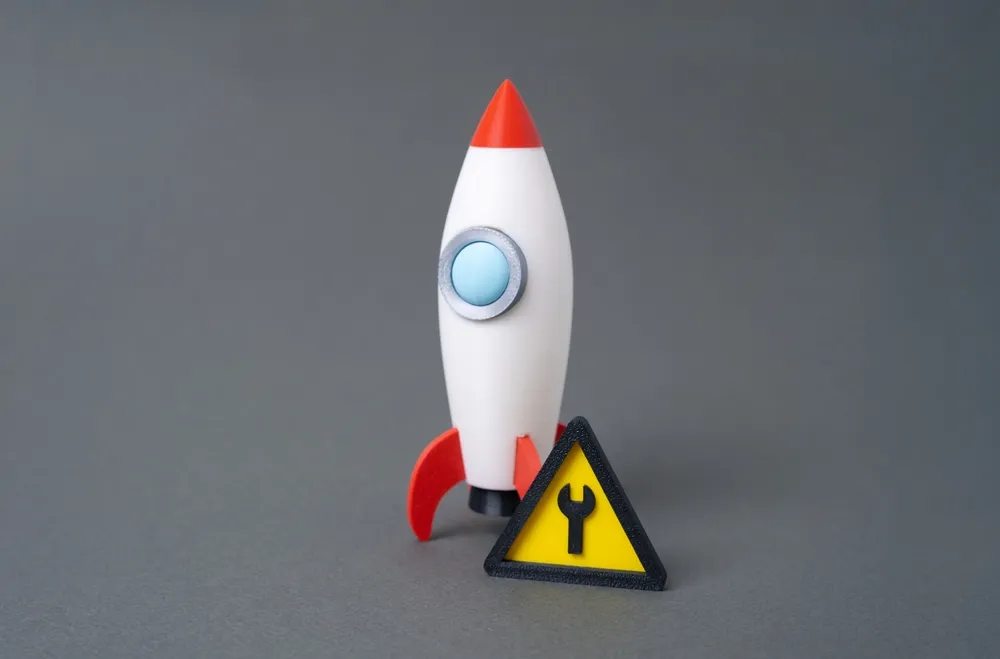 A toy rocket on the launch pad beside a small repair sign